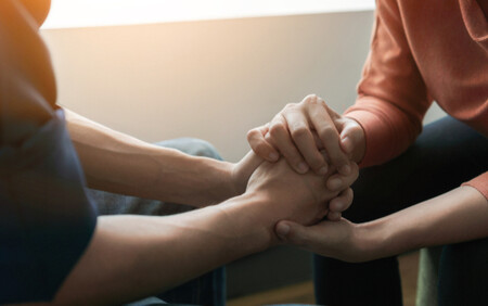 two people holding hands in a supportive setting